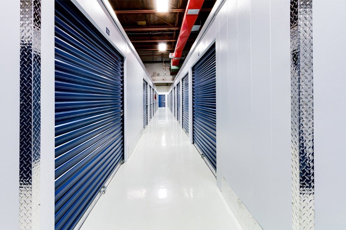 Bright hallway of blue roll-up storage unit doors at CityBox Manchester